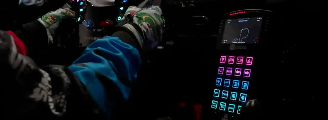 Cockpit photo while driving: gloved hands on the wheel and the deck beside it with every key lit with its action icon.
